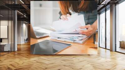 Businesswoman working in Stacks of paper files for searching and checking unfinished document achieves on folders papers at busy work desk office. Wall mural