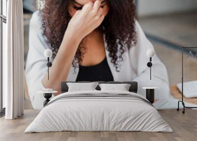 Overworked professional woman showing signs of stress and headache while working on her laptop in a modern office. Wall mural