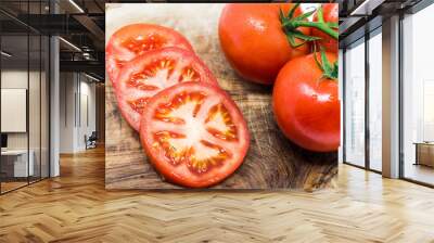 Slice tomato and fresh tomatoes on the vine on cutting board. Wall mural