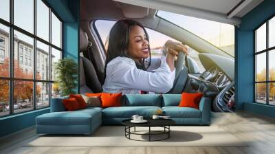 Beautiful smiling African-American woman inside a car leaning on the steering wheel Wall mural