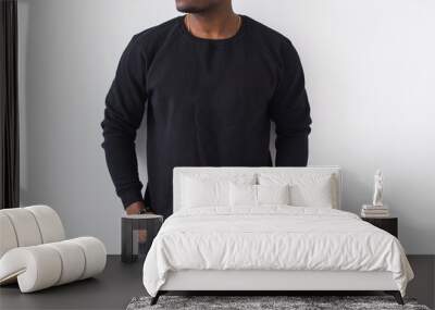 Close-up of n African American man posing in black sweatshirt on a white background. Youth street fashion photo with afro hairstyle. Wall mural