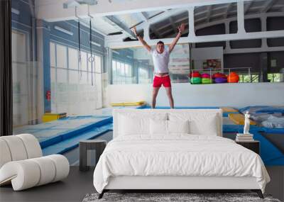 Fitness, fun, leisure and sport activity concept - Handsome happy man jumping on a trampoline indoors Wall mural