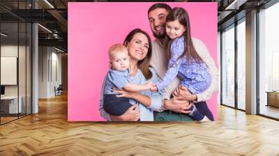 Happy mixed race family portrait smiling on pink background Wall mural