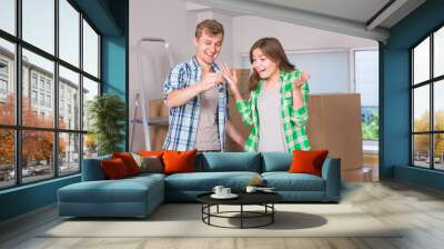 Happy young couple moving in a new house. Housewarming, real estate and people concept Wall mural