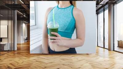 Healthy, fitness and detox concept - close up of young woman in sports wear with green smoothie indoors Wall mural