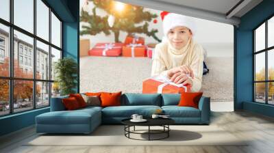 Holidays, christmas, childhood and people concept - smiling happy teen boy in santa hat with gift box over christmas tree background Wall mural