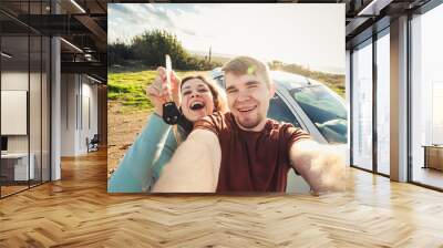 portrait of happy beautiful couple showingh the keys standing near the car Wall mural