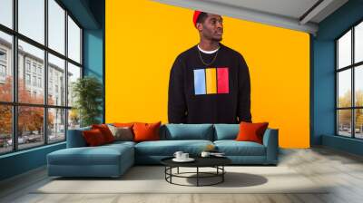 Street fashion concept - Studio shot of young handsome African man wearing sweatshirt against yellow background. Wall mural