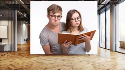 Studying together and people concept - a couple of young funny people reading a book Wall mural