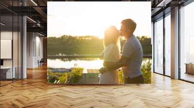 Wonderful young couple hug and enjoy life together with natural outdoor leisure activity lifestyle on nature and the sunset in backlight. Wall mural