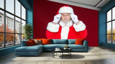 Christmas. Serious Santa Claus in white gloves adjusts her glasses and stares into the camera. Isolated on red background. Wall mural