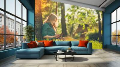 pretty young caucasian woman sitting outside under a tree Wall mural