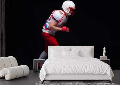 Side view of American football player wearing helmet taking position while playing against black background Wall mural