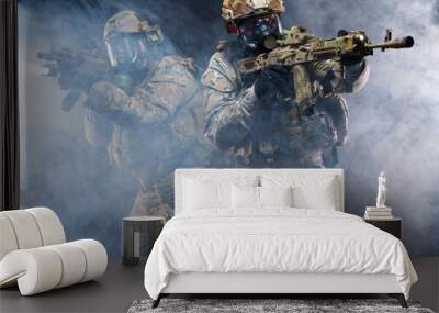 Two soldiers in military gear, bulletproof vests and gas masks cover each other and raise their submachine guns taking aim, in full combat readiness to break through the smoke from chemical weapons Wall mural