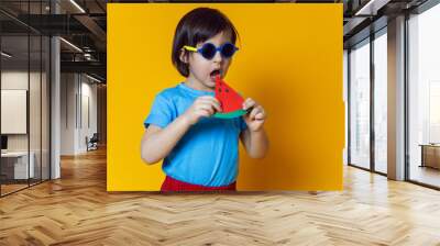 baby boy in red pants eats a paper watermelon on a yellow background Wall mural