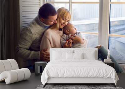 family in warm sweaters with his son sitting on the window in the winter Wall mural