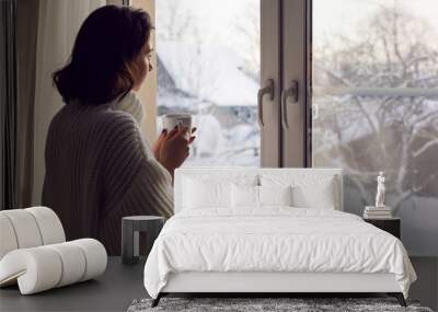 girl in a white knitted sweater stands at the window Wall mural