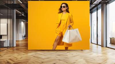 full body beautiful asian woman carrying shopping bags with bright yellow background isolated Wall mural