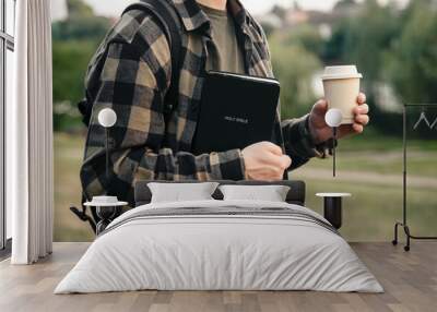 Bible and paper cup in the hands of a Christian man outside. Wall mural