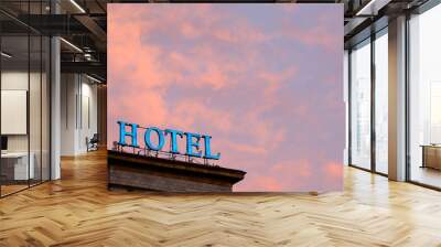 Weathered and burned out neon hotel sign lit up against a colorful and dramatic red and orange sky at sunset in New York Wall mural