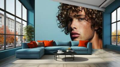 Young Man with Curly Hair and Intense Blue Eyes Wall mural