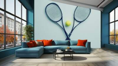 A flat lay of two crossed tennis racquets with a tennis ball in the middle, isolated on a white background, highlighting the simplicity of the sport. Wall mural