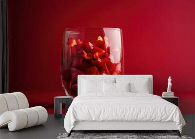 A fresh perspective on culinary ingredients, showcasing red pepper pieces in a glass with a vibrant red backdrop. Wall mural