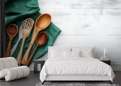 A green tablecloth and cooking utensils spread on a white wooden table, leaving empty space in the middle for text or product montage. Wall mural