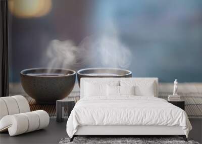 A pair of small tea cups filled with steaming tea, placed on a bamboo mat with soft lighting. Wall mural