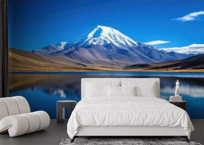 A stunning snow-capped mountain reflected in a glassy lake, framed by clear blue skies. Wall mural