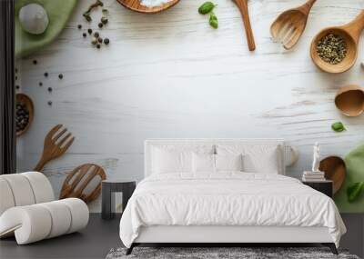 A white wooden table covered with a green tablecloth and scattered with cooking utensils. Empty space at the center for text or product placement. Wall mural