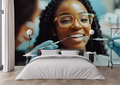 African American female dentist using dental instruments to examine her patient's teeth. Bright, professional dental office Wall mural