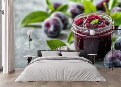 Fresh plums next to a jar of homemade plum jam on a clean kitchen surface, emphasizing artisanal and fresh flavors Wall mural