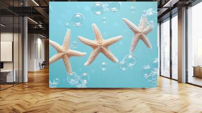 Three delicate starfish on a pastel blue background, with bubbles floating in a soft ocean-inspired design Wall mural