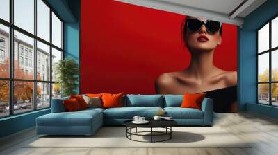 Woman in black dress and dark sunglasses posing confidently on a red background, stylish banner concept, modern minimalism, high-end look Wall mural