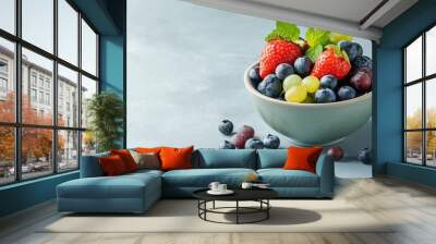 A bowl filled with fresh strawberries, blueberries, and green grapes, a healthy and delicious snack or dessert. Wall mural