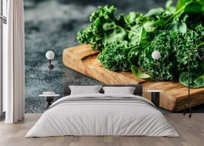 A close-up of fresh kale and spinach leaves arranged on a rustic wooden cutting board, symbolizing health, vitality, and a healthy lifestyle.  The dark background enhances the vibrant green color of t Wall mural