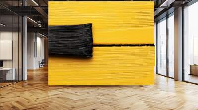 A paintbrush lies on a yellow wooden surface, symbolizing repair, renovation, restoration, DIY projects, and new beginnings., A paintbrush lies on a yellow wooden surface, symbolizing repair Wall mural