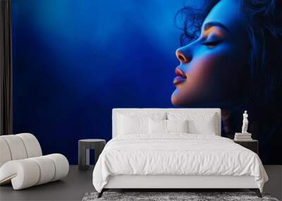 A serene portrait of a dreamy young woman with closed eyes bathed in blue light, symbolizing peace, tranquility, mystery, and hope. Wall mural