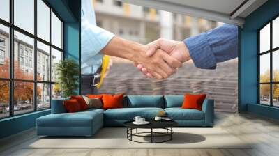 Two construction engineers shaking hands on building site background, partnership concept Wall mural