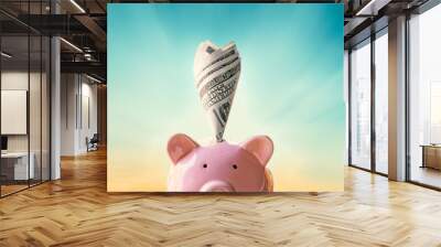 Piggy bank with money on sky sunset background saving concept. Wall mural