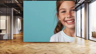 One smiling teeth happy young 10 yr old girl portrait long hair in braid lifestyle education wellness concept campaign isolated on blank blue studio background copy space fun caucasian Australian Wall mural