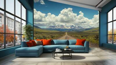 A stunning view of an endless dirt road that leads to majestic mountains, with a sky full of fluffy white clouds. Wall mural