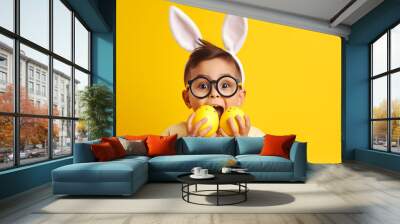 funny happy child boy with easter eggs and bunny ears on yellow background  Wall mural