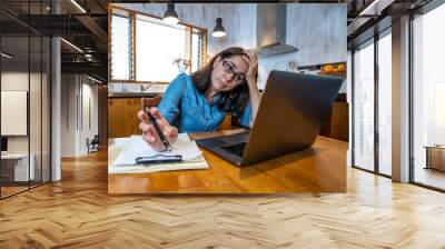 Attractive young business woman working from home on her computer stressed, tired and overwhelmed Wall mural