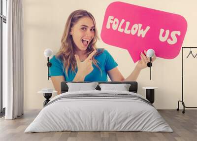 Beautiful young woman holding follow us social media icon for her business on the internet Wall mural