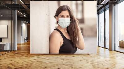 Portrait of attractive young happy woman with protective surgical face mask in public spaces Wall mural