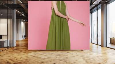 High fashion photo of a beautiful elegant young skinny woman in pretty long green dress posing on pink background. Slim figure. Wall mural