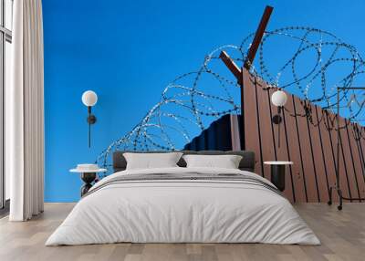 brown fence with barbed wire, prison or guarded area against blue sky Wall mural