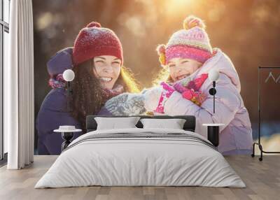 Little girl and her mother playing outdoors at sunny winter day. Active winter holydays concept. Wall mural